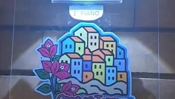 Una placa de vidrio transparente con una ilustración colorida de casas y flores, con la etiqueta '1st Piano' y 'Carne Tarra in Hore'.