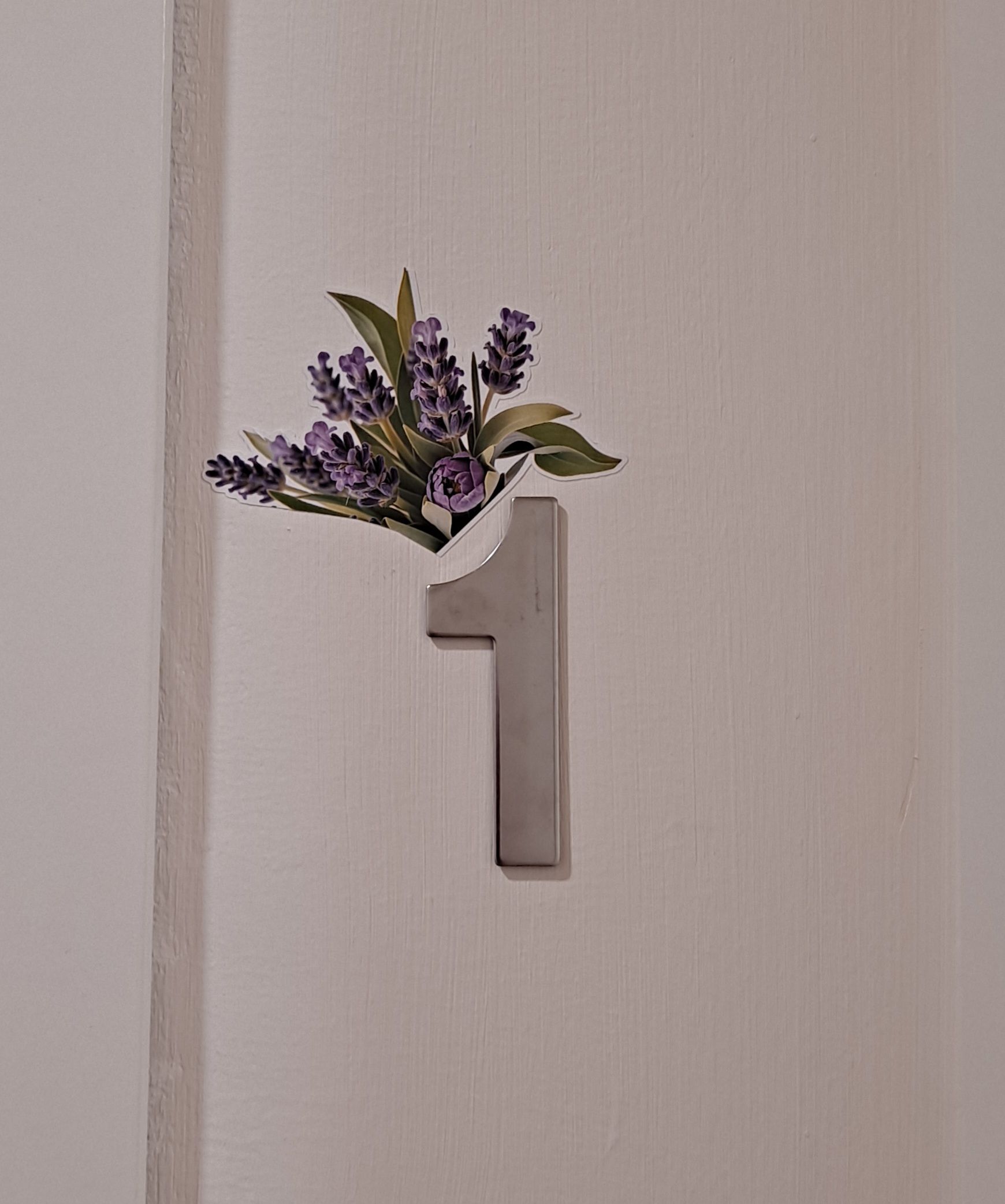 Une porte portant le numéro « 1 » et ornée d’une composition florale décorative.