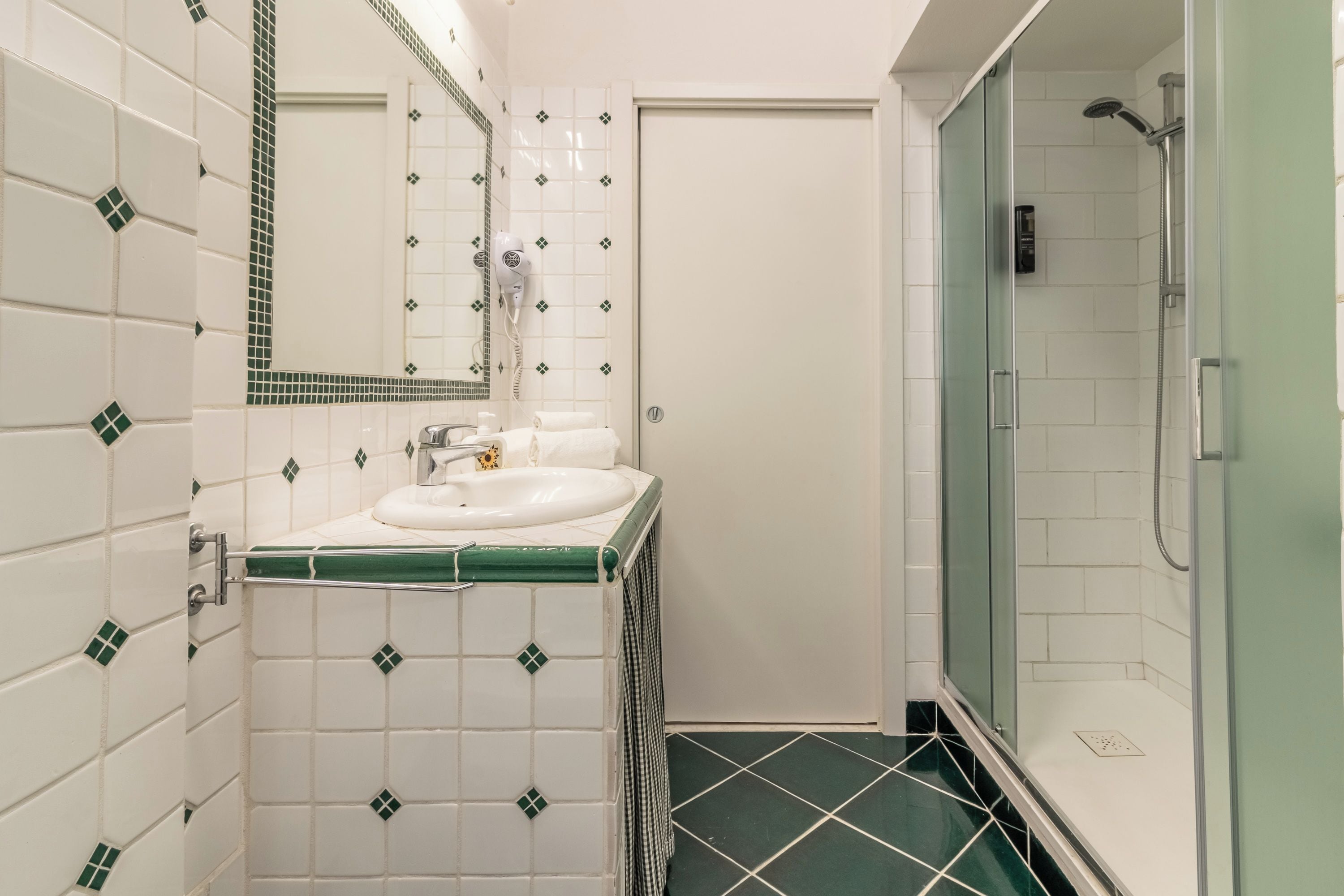 Un bagno con un lavandino bianco, uno specchio e una zona doccia.
