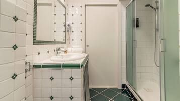 Un bagno con un lavandino bianco, uno specchio e una zona doccia.