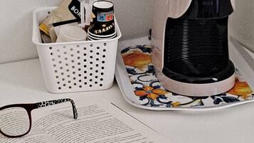 Une machine à café, un panier rempli d’objets et un livre ouvert sur une table.