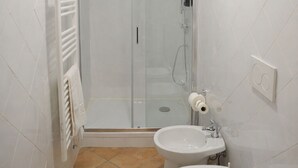 Une salle de bain avec une douche à parois de verre, des toilettes et un lavabo.