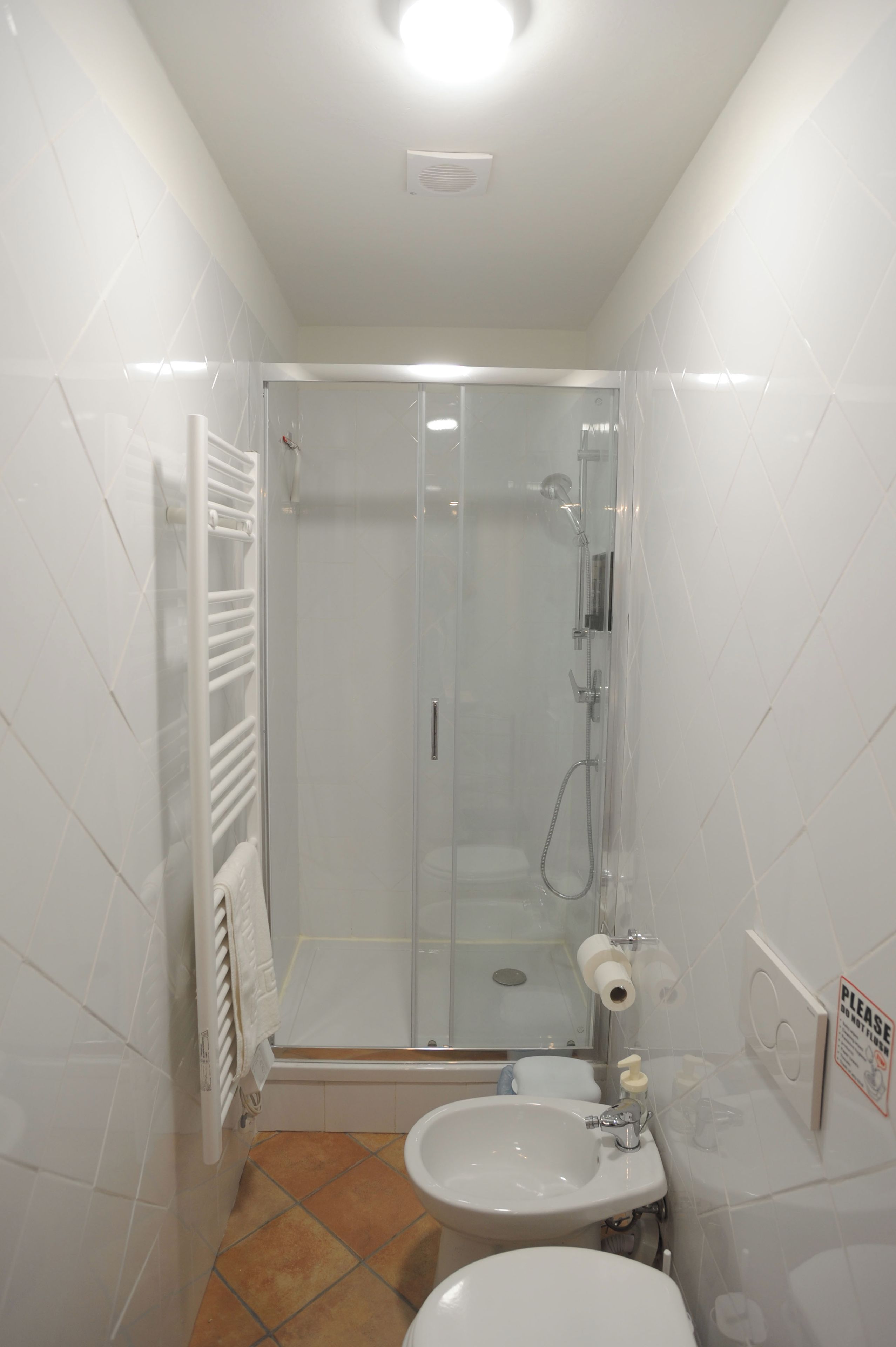 A bathroom with a glass-enclosed shower, a white sink, and a toilet.
