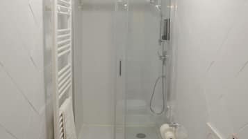 Ein Badezimmer mit einer Duschkabine, einem weißen Waschbecken und einer Toilette.