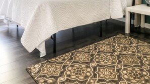 A bedroom with a bed, bedside table, and a patterned rug. - Tucked away in Tucker (Tucker)