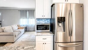 A modern kitchen with stainless steel appliances, white cabinetry, and a marble countertop. - Tucked away in Tucker (Tucker)