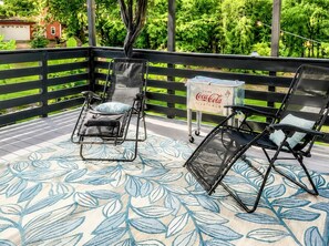 Eine Terrasse mit zwei Liegestühlen und einem Kühlkasten für Cola.