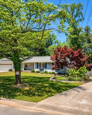 Une maison d’habitation avec un jardin devant, une allée et un garage.