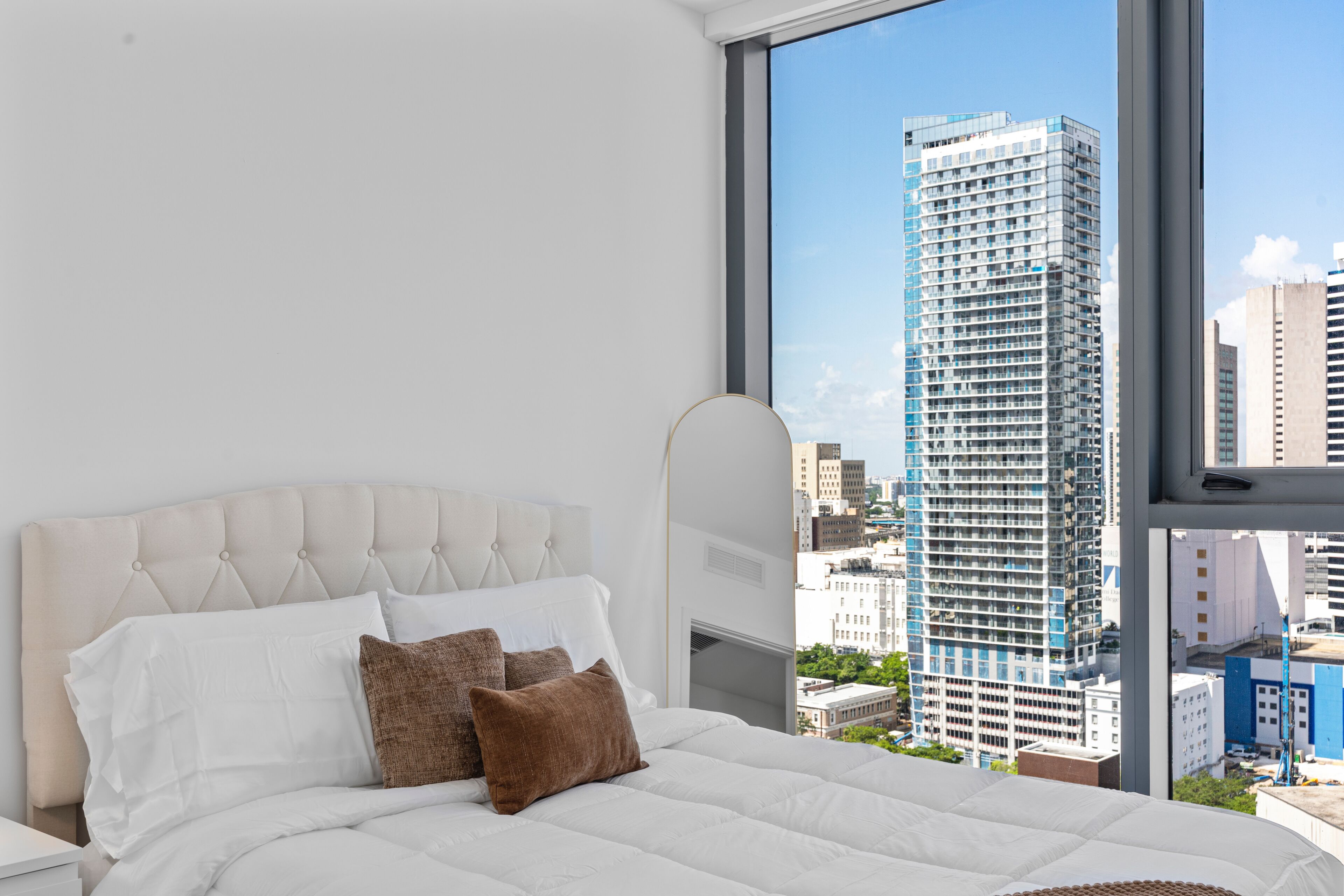 A hotel room with a large bed, a view of a tall building, and a window.