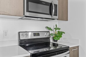 A kitchen with a stainless steel microwave, a digital oven control panel, and a black induction cooktop. - 2-bedroom condo in marvelous Miami Views in the perfect spot! (Miami)
