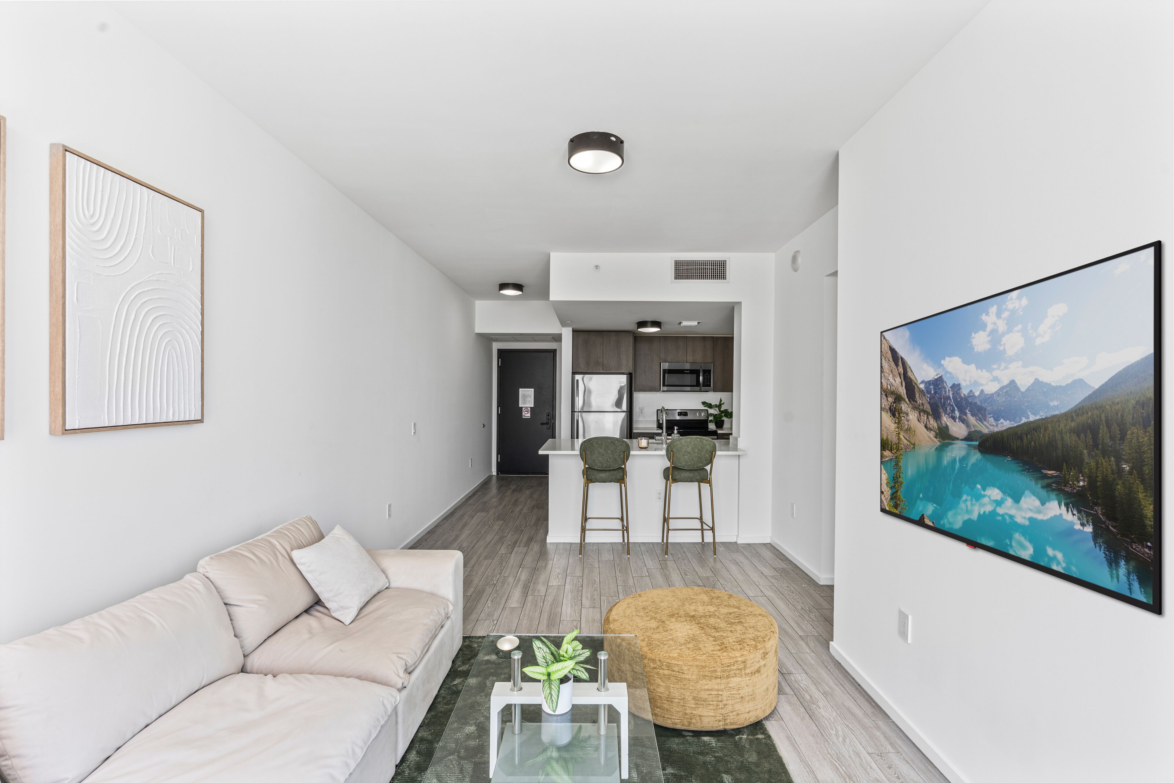 A modern living room with a sofa, a coffee table, and a painting of a mountain lake.