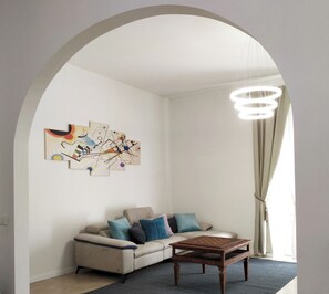 A living room with a sofa, a coffee table, and a wall art piece. - Essenza Maison***** Spacious apartment in the ❤️ of Pescara, just a few meters from the sea. (Pescara)