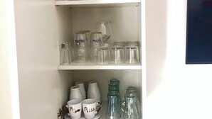 A white cabinet with shelves containing glassware, a diffuser, and a teal vase. - Essenza Maison***** Spacious apartment in the ❤️ of Pescara, just a few meters from the sea. (Pescara)