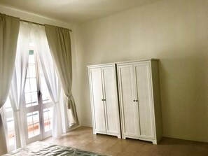 Ein Zimmer mit einem Bett, einem Schrank und einem fensterbepflanzten Fenster.