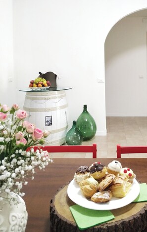 Ein Essbereich mit einem Tisch, der für eine Mahlzeit gedeckt ist, einer Blumenvase und einem weißen Schrank mit Glasplatte.