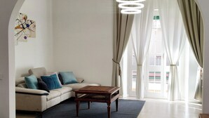 A living room with a sofa, a coffee table, a rug, and a chandelier. - Essenza Maison***** Spacious apartment in the ❤️ of Pescara, just a few meters from the sea. (Pescara)