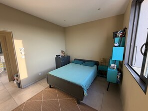 A bedroom with a bed, a nightstand, a dresser, and a window. - Vacation Home for Rent (Belgodère)
