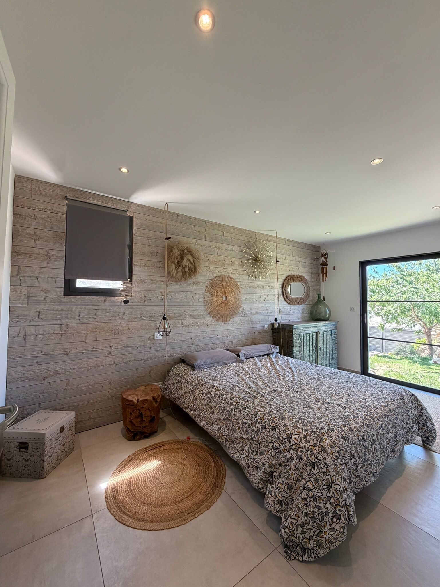 A modern bedroom with a large bed, a wooden wall, and a view of the outdoors.