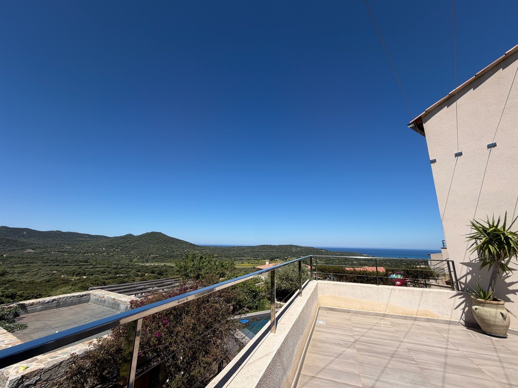 Un balcon offrant une vue sur un paysage montagneux et la mer.