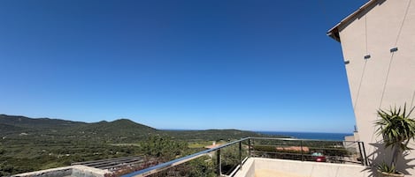 A balcony with a view of a mountainous landscape and the sea.