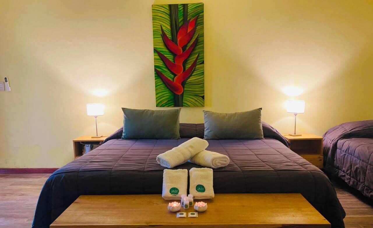 Een hotelkamer met een groot bed, twee nachtkastjes, een houten bankje en een wanddecoratie.