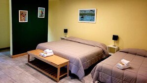 Habitación de hotel con dos camas, una mesita y obras de arte en las paredes.