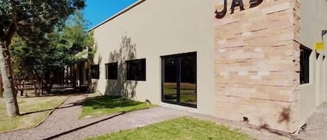 Um edifício com o nome 'JASY' na fachada, entrada pavimentada e área gramada frontal.