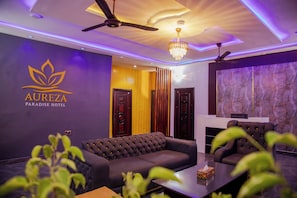 A modern hotel lobby with a sofa, a chandelier, and a reception desk. - Aureza Paradise Hotel (Tamale)
