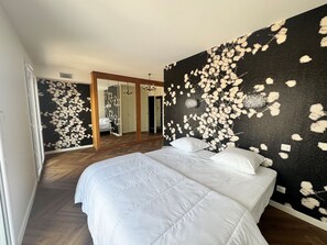 Un dormitorio con una cama grande, un espejo y una pared con estampado floral.