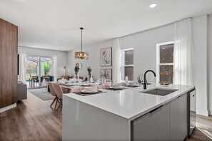 Une cuisine moderne dotée d’un grand îlot central, de meubles blancs et d’un lave-vaisselle encastré.