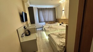 Een hotelkamer met een bed, een bureau, een televisie en een raam met gordijnen.