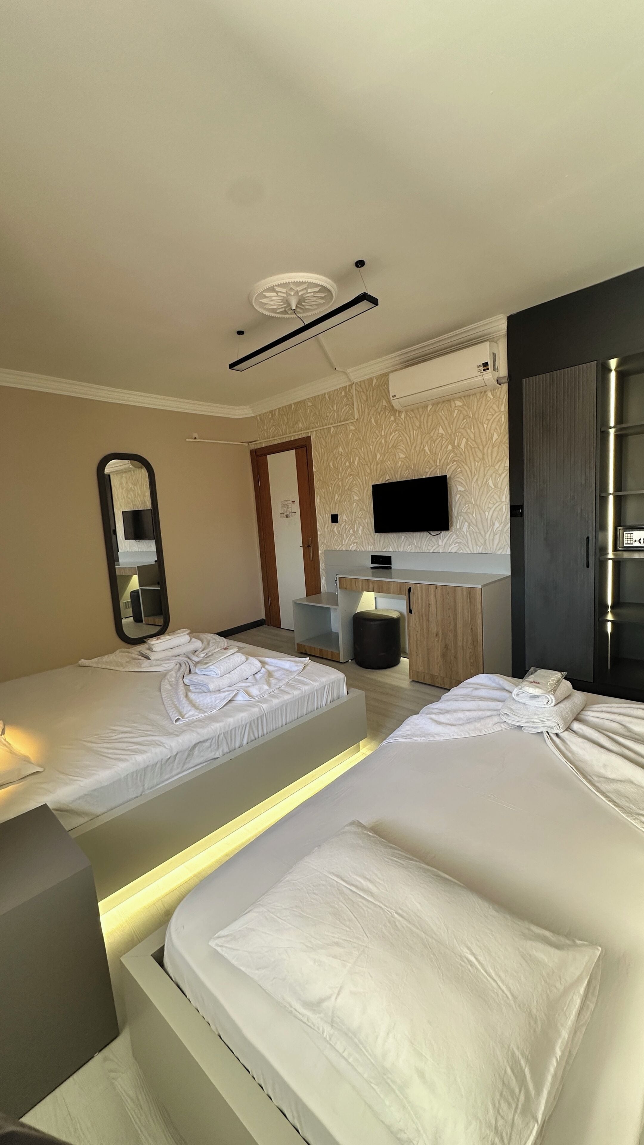 Ett hotellrum med två sängar, en platt-TV, en spegel och ett skrivbord med en stol.