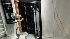Een badkamer met toilet, wastafel, spiegel en douchehoek.