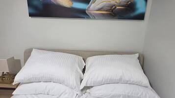 A bedroom with a bed, pillows, and a wall-mounted painting of swans.