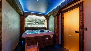 A room with a starry ceiling, a hot tub, and a window with a mountain view.