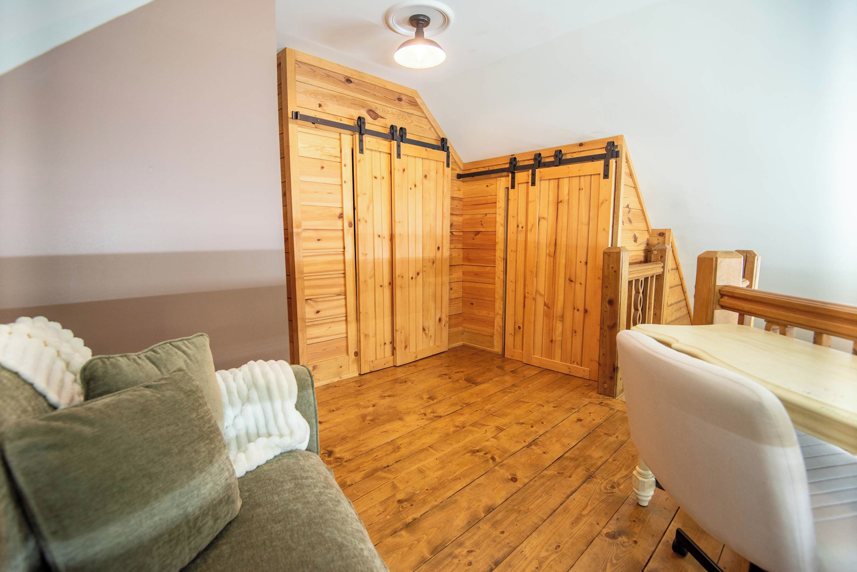 Een kamer met houten vloeren, een bank, een bed en een set houten schuifdeuren.