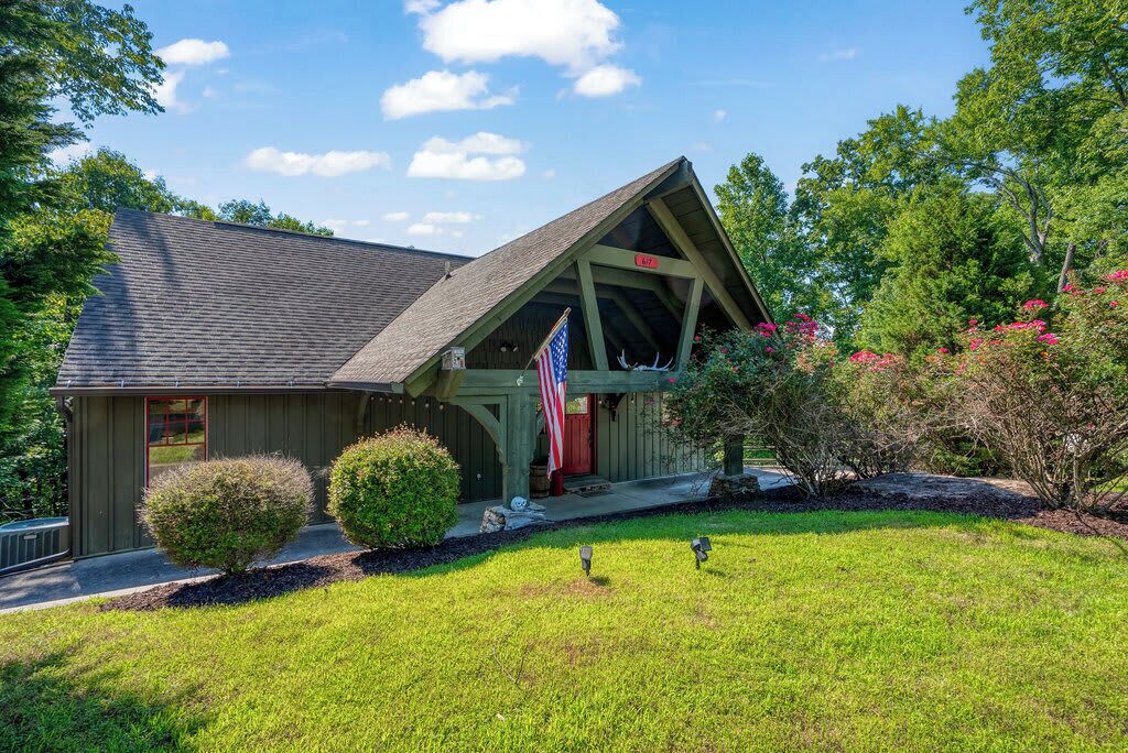 A building with a sloped roof, a porch with a railing, and an American flag.