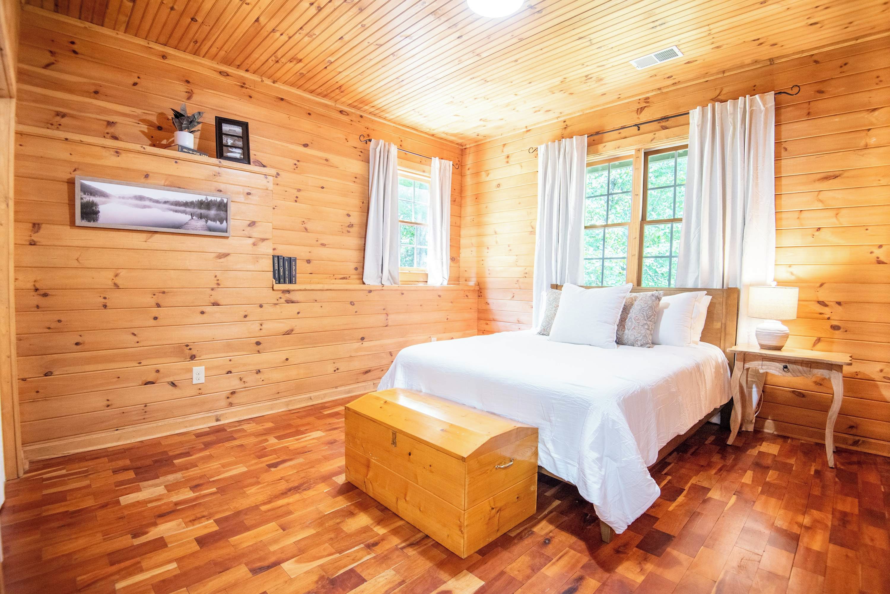 A wooden cabin bedroom with a bed, nightstand, and a chest of drawers.