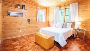 A wooden cabin bedroom with a bed, nightstand, and a chest of drawers. - *NEW!* Cozy Watts Bar Getaway for Families & Friends (Rhea County)