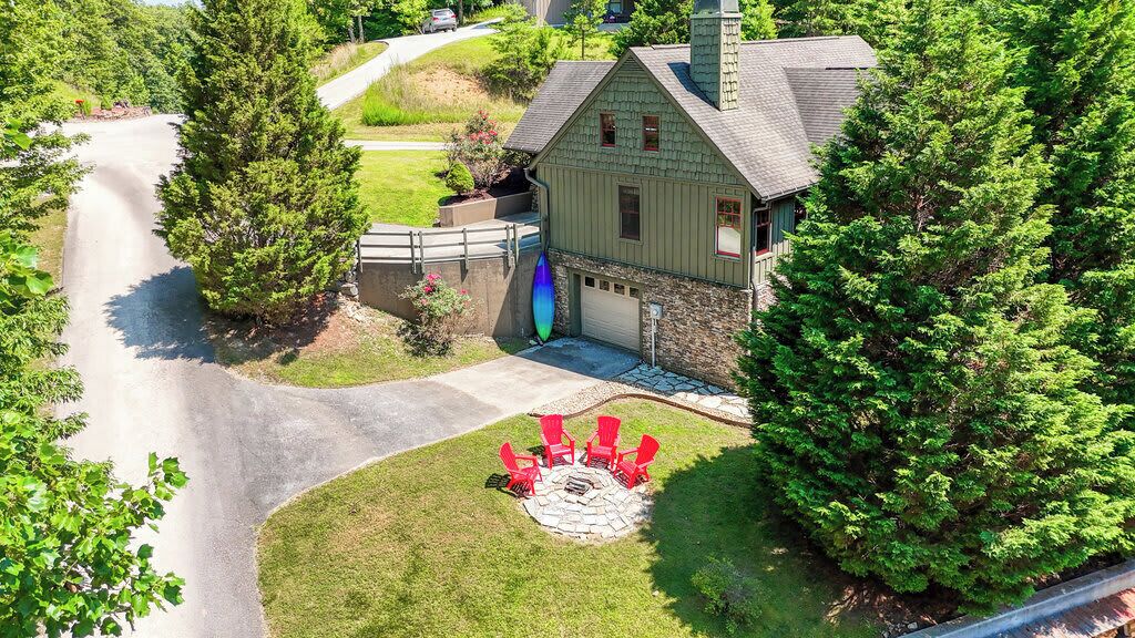 A house with a stone fireplace, a driveway, and a surrounding lawn.
