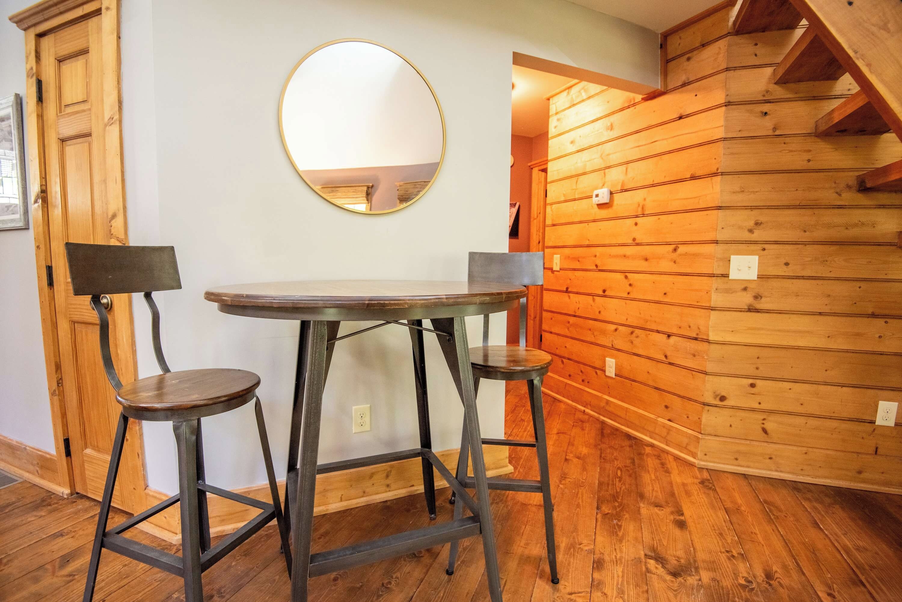 A room with a round table and two chairs, a wooden wall, and a door.