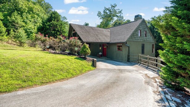 A two-story house with a red door, a front porch, and a driveway leading to a wooden fence. - *NEW!* Cozy Watts Bar Getaway for Families & Friends (Rhea County)