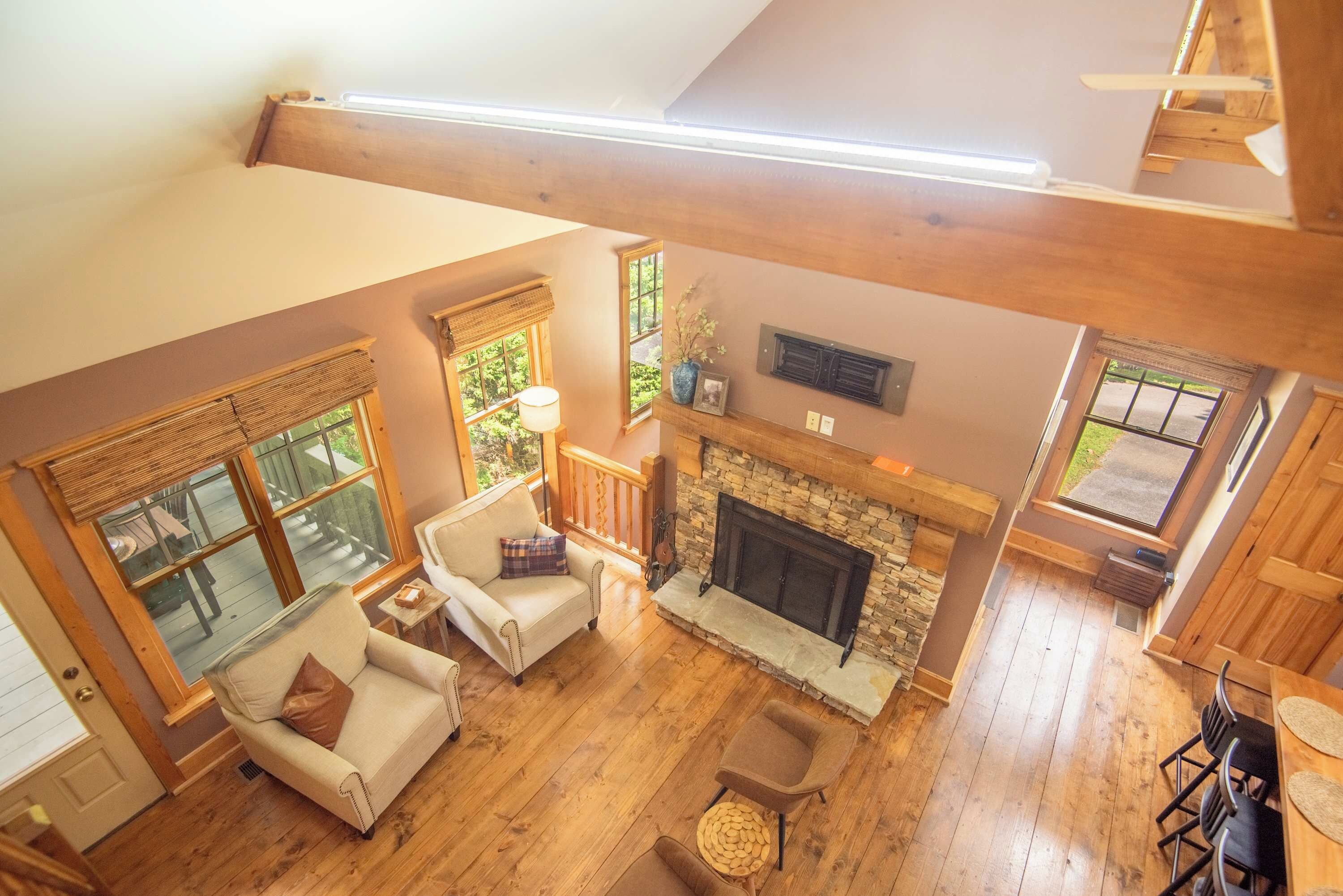 A spacious loft with high ceilings, large windows, a fireplace, and a cozy seating area.