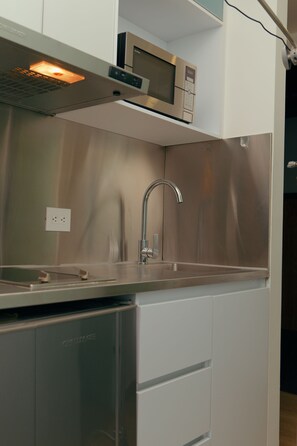 Una cocina con electrodomésticos de acero inoxidable, incluyendo un microondas, un lavaplatos y un fregadero.