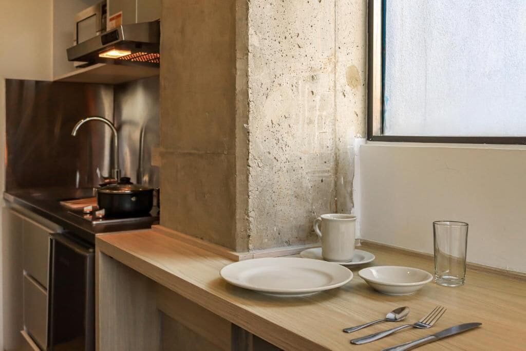 Cocina con campana de acero inoxidable, protector contra salpicaduras de concreto y encimera de madera.