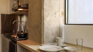 A kitchen with a stainless steel range hood, a concrete backsplash, and a wooden countertop. - Hotel Happa Hub (Bogota)