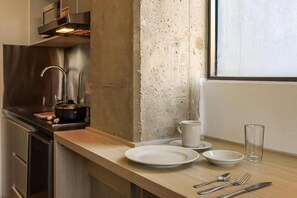 A kitchen with a stainless steel range hood, a concrete backsplash, and a wooden countertop. - Hotel Happa Hub (Bogota)