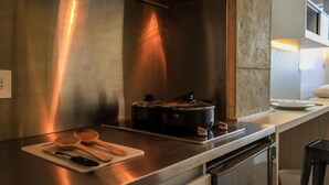 A modern kitchen with stainless steel appliances, a cutting board with wooden utensils, and a dishwasher. - Hotel Happa Hub (Bogota)