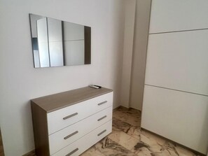 Une pièce comprenant une commode blanche, un miroir et une armoire.