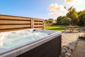 Ein Whirlpool in einer Außenanlage mit einer Holzterrasse und einer Steinpatio.